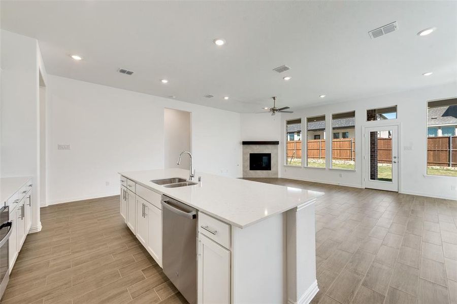 Kitchen featuring stainless steel dishwasher, sink, ceiling fan, and plenty of natural light