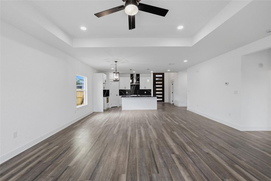 Living with raised ceiling, ceiling fan, and recessed lighting