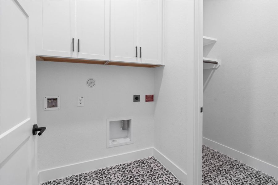This bright and functional laundry room is conveniently located and ready for your appliances. It features clean white walls, trim and cabinetry to fit your laundry supplies, and the gorgeous decorative tile flooring for durability.