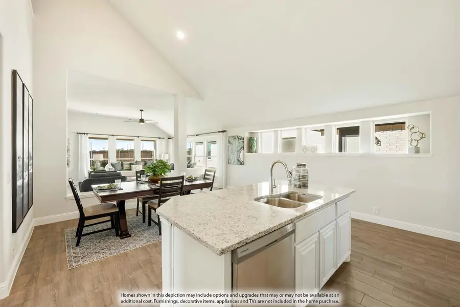 Kitchen island with granite countertop and sink, open to dining and living areas with vaulted ceiling and hardwood floors