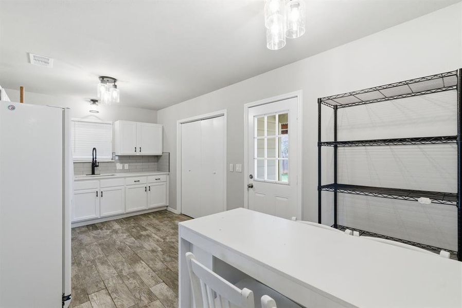 Kitchen with freestanding refrigerator, white cabinetry, light wood finished floors, tasteful backsplash, and light countertops Kitchen with freestanding refrigerator, white cabinetry, light wood finished floors, tasteful backsplash, and light countertops