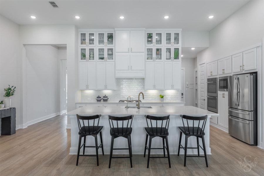 This showstopping kitchen is anchored by an expansive quartz island with breakfast bar. Floor-to-ceiling cabinetry, glass-front displays and warm gold hardware create an unforgettable luxury statement. This showstopping kitchen is anchored by an expansive quartz island with breakfast bar. Floor-to-ceiling cabinetry, glass-front displays and warm gold hardware create an unforgettable luxury statement.