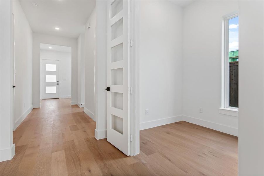 Hallway featuring built in shelves and light wood-type flooring