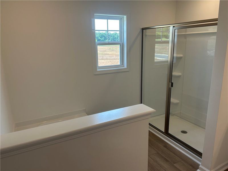 A well-lit primary bathroom featuring wood-look fl