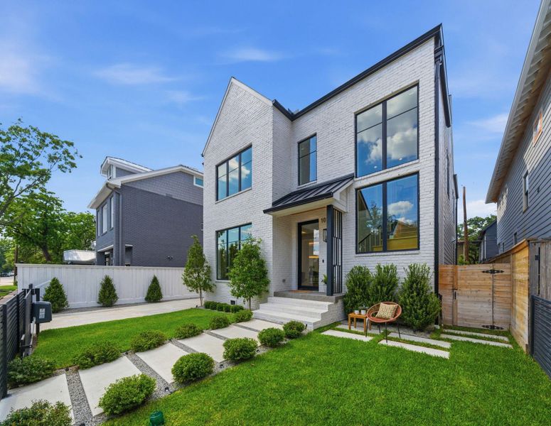 Welcoming front entry with lush landscaping, modern steel accents, and charming outdoor seating area. Welcoming front entry with lush landscaping, modern steel accents, and charming outdoor seating area.
