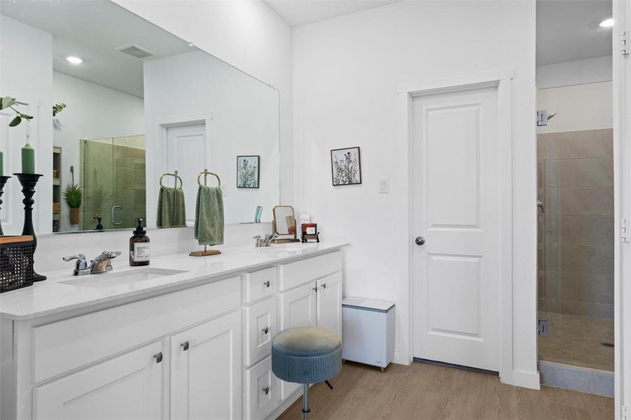 Full bathroom featuring a shower stall, double vanity, light LVP type flooring, and recessed lighting Full bathroom featuring a shower stall, double vanity, light LVP type flooring, and recessed lighting
