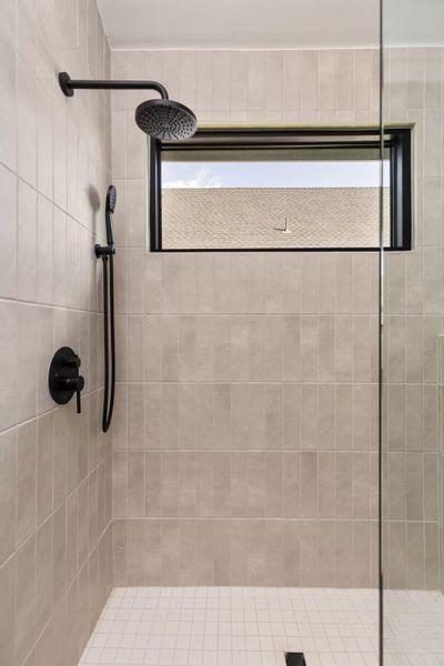 Modern shower stall features sleek black fixtures and a window for natural light.