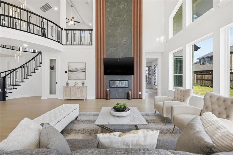 Spacious living area featuring a two-story ceiling, light wood-finish flooring, and expansive windows