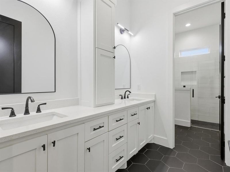 Full bathroom on first level with dual vanity with white cabinetry, quartz countertops, and matte black fixtures