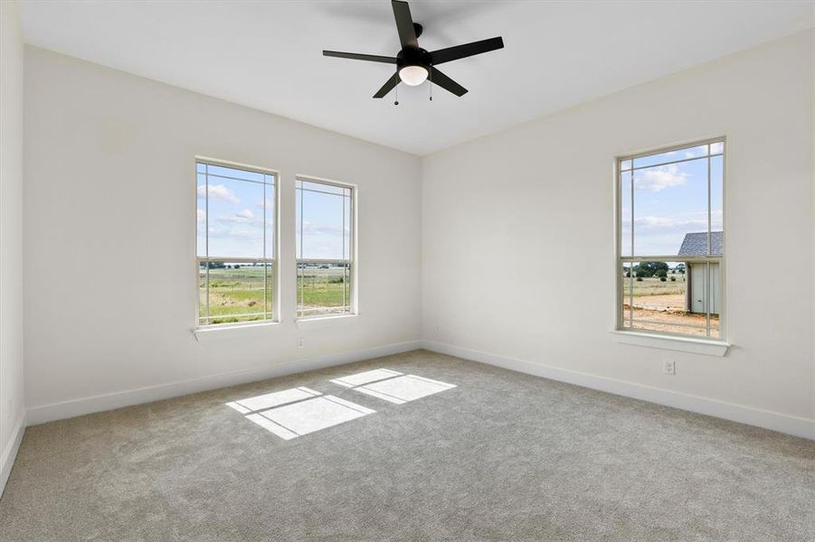 Unfurnished room featuring healthy amount of natural light, carpet flooring, and a ceiling fan Unfurnished room featuring healthy amount of natural light, carpet flooring, and a ceiling fan
