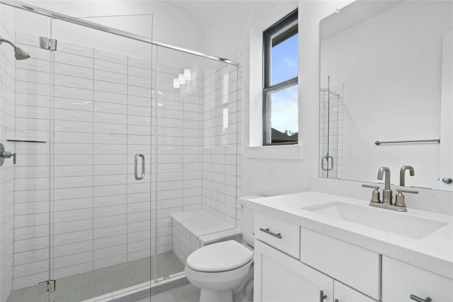 This ensuite secondary bathroom features a modern vanity, large walk-in shower with seat and tile surround, and brushed nickel finishes. This ensuite secondary bathroom features a modern vanity, large walk-in shower with seat and tile surround, and brushed nickel finishes.