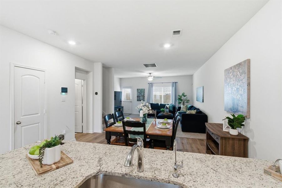 Open concept living area with light walls, recessed lighting, and wood-look flooring