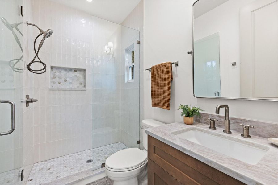 A well-appointed bathroom features a glass-enclosed shower and a sleek vanity with a basin sink.
