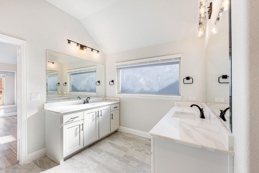 Bathroom with white double vanity, marble countertops, soaking tub, and vaulted ceiling with tile floors Bathroom with white double vanity, marble countertops, soaking tub, and vaulted ceiling with tile floors