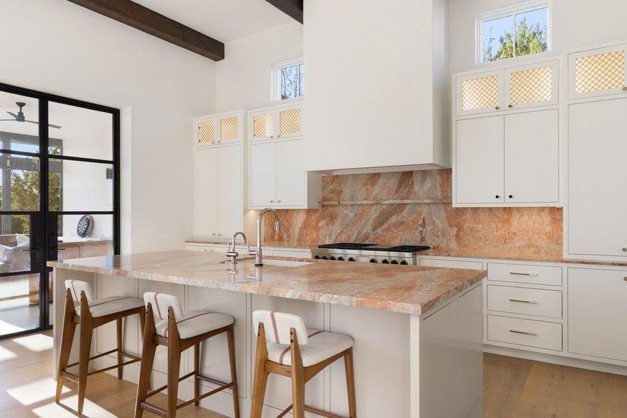 Kitchen featuring plenty of natural light, glass insert cabinets, a breakfast bar area, and light wood-type flooring