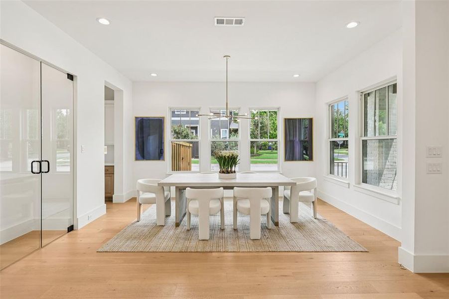 Spacious room featuring light wood-finish flooring, recessed lighting, and multiple windows