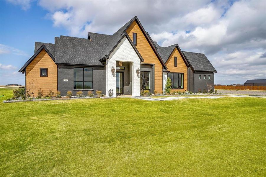 View of front facade with a front lawn, brick siding, and roof with shingles