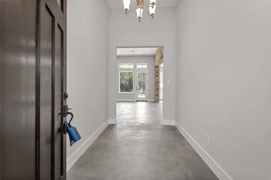 Step into the inviting foyer where sleek sealed concrete flooring immediately makes a statement. This durable and stylish finish flows seamlessly throughout the home, creating a cohesive look while offering low-maintenance convenience.The smooth, polished surface adds a modern touch with subtle texture and warmth, complementing the home’s architectural details. Designed for both beauty and practicality, the sealed concrete floors provide lasting durability.