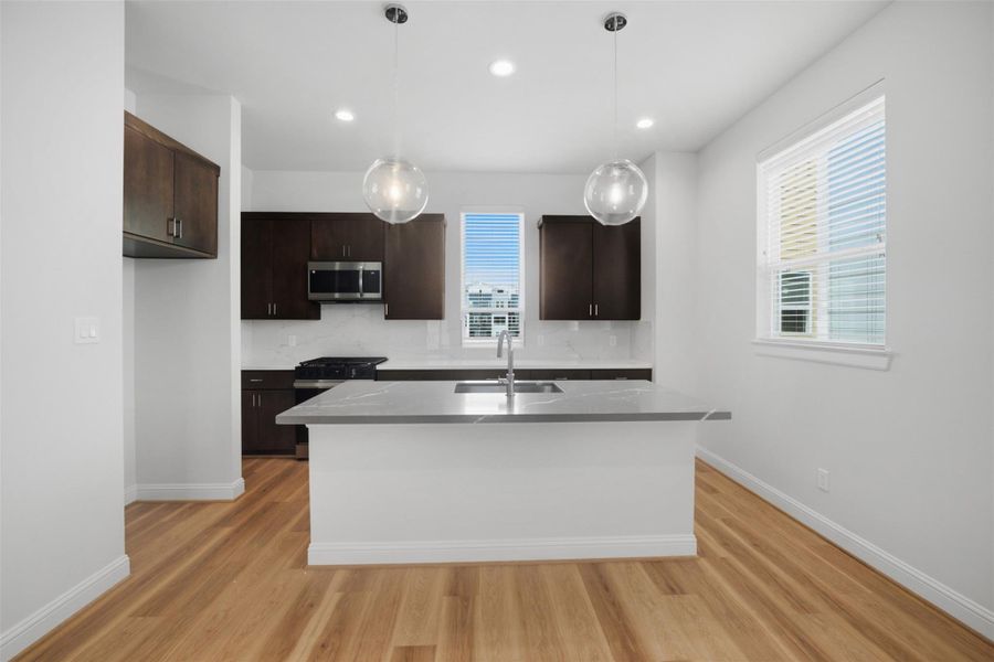 Discover culinary bliss in this sleek kitchen featuring dark wood cabinetry, modern stainless steel appliances, and a spacious island perfect for entertaining.