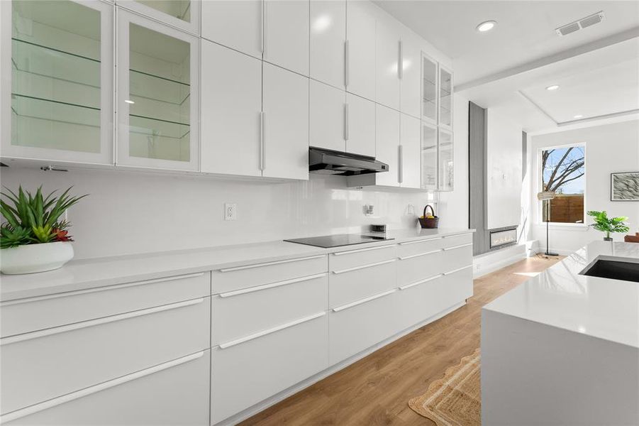 Kitchen featuring glass insert cabinets, white cabinets, modern cabinets, and recessed lighting