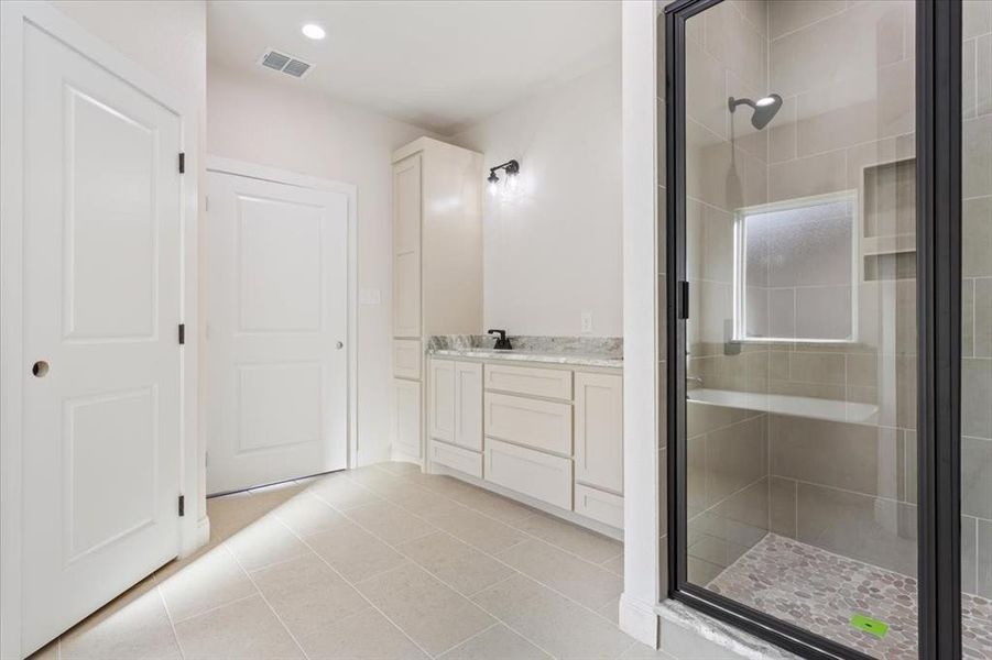 Bathroom featuring a stall shower, vanity, light tile patterned floors, and recessed lighting