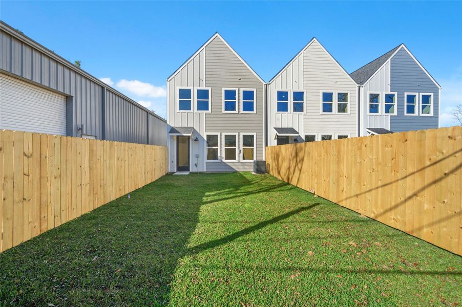 Fenced backyard, featuring a spacious lawn and contemporary exterior design. Ideal for privacy and outdoor enjoyment.