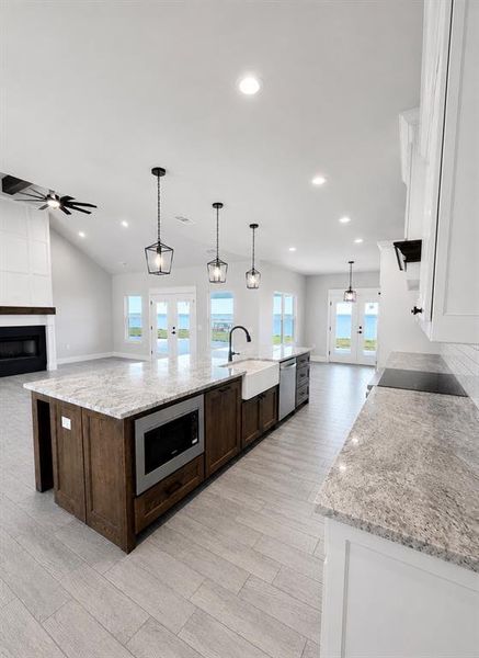 Spacious open-concept kitchen featuring an expansive center island with integrated microwave, farmhouse sink, and dishwasher Spacious open-concept kitchen featuring an expansive center island with integrated microwave, farmhouse sink, and dishwasher