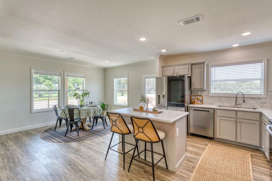 An open-concept living area with bright windows connects a modern kitchen to a charming dining space. An open-concept living area with bright windows connects a modern kitchen to a charming dining space.