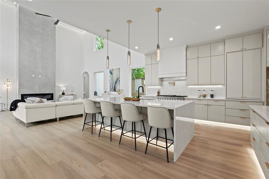 Kitchen with modern cabinets, a kitchen bar, light wood finished floors, a high ceiling, and white cabinetry