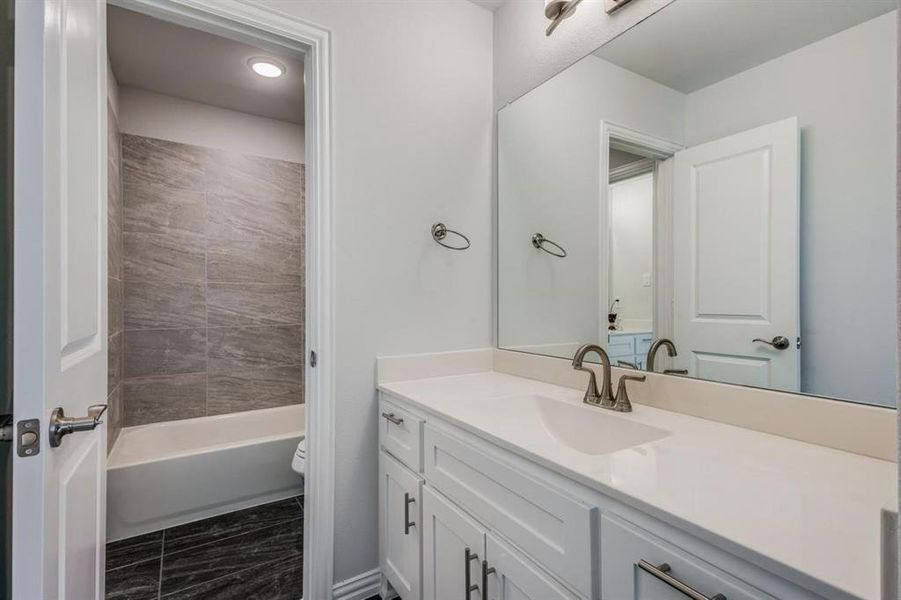 Full bathroom featuring vanity, tiled shower / bath, and toilet