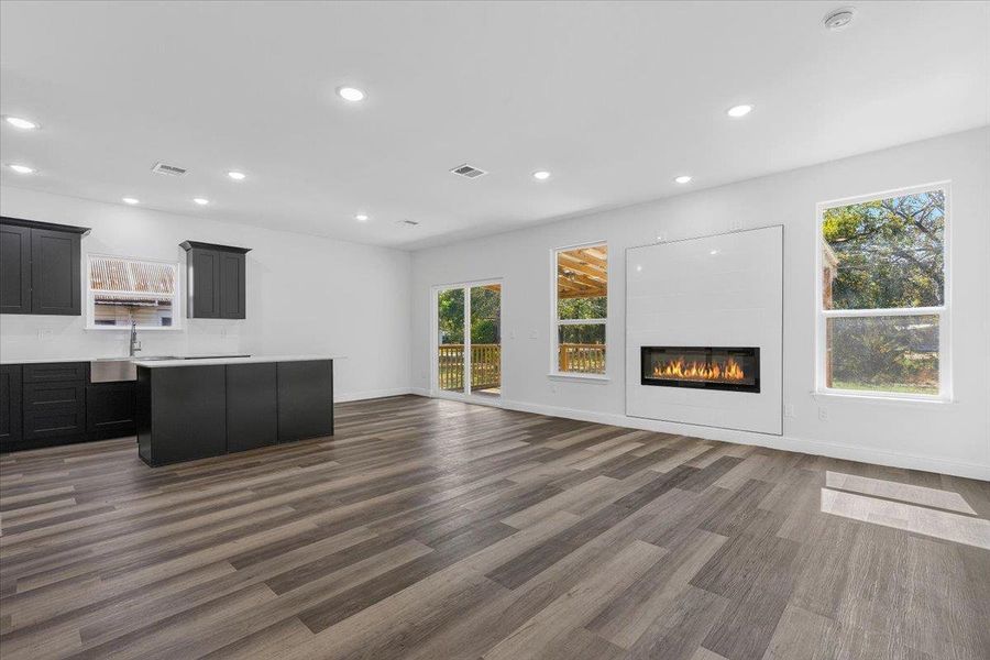 An open floor plan integrates a modern kitchen with a living area featuring a sleek fireplace. An open floor plan integrates a modern kitchen with a living area featuring a sleek fireplace.