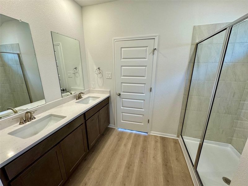 Bathroom with wood finished floors, double vanity, and tiled shower Bathroom with wood finished floors, double vanity, and tiled shower