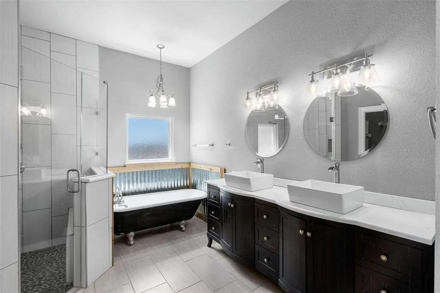 Bathroom featuring double vanity, a freestanding tub, a shower stall, and a textured wall
