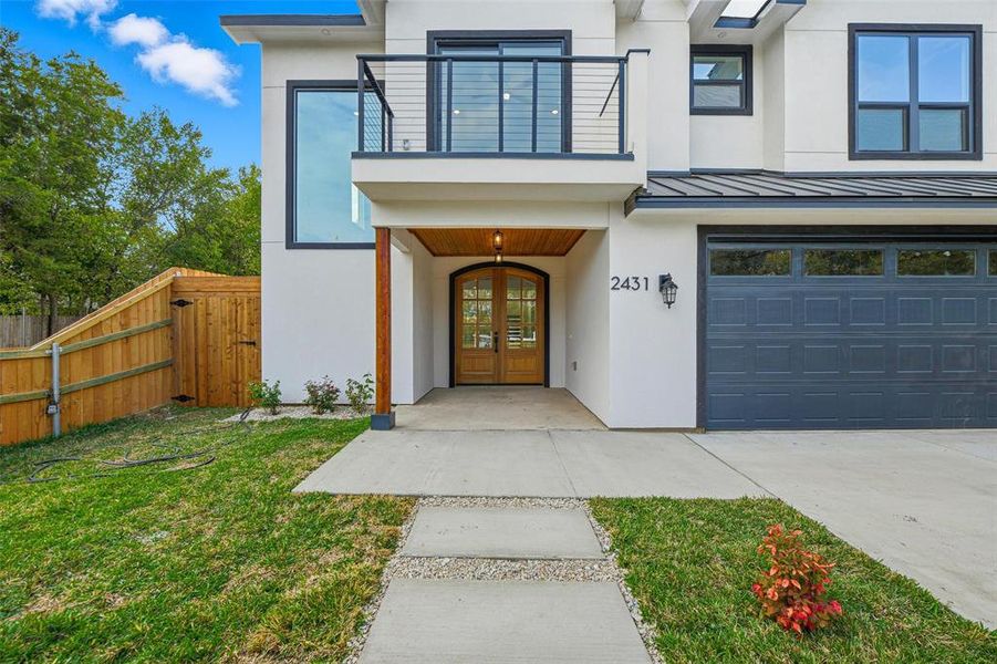 View of exterior entry featuring stucco siding, a standing seam roof, a metal roof, an attached garage, and a gate