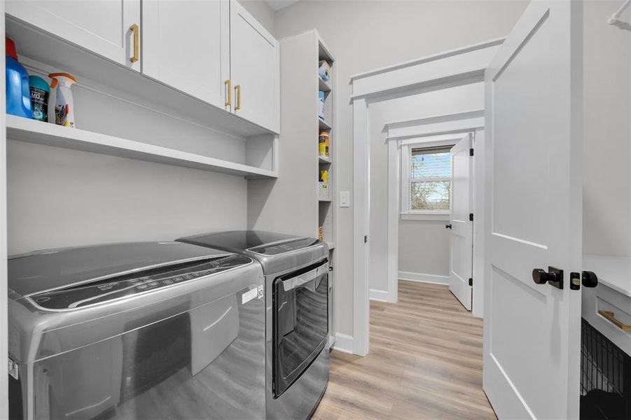 Laundry room featuring cabinets, light hardwood / wood-style floors, and washer and clothes dryer