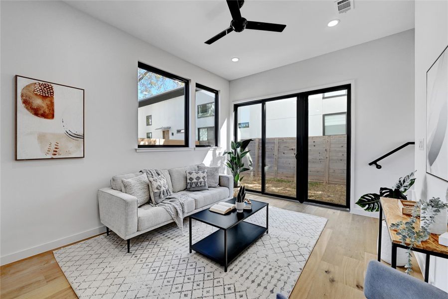 Living room with ceiling fan and light hardwood / wood-style flooring