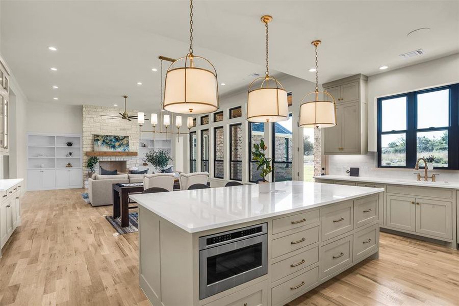 Kitchen featuring pendant lighting, gray cabinetry, light wood-style floors, light stone countertops, and recessed lighting