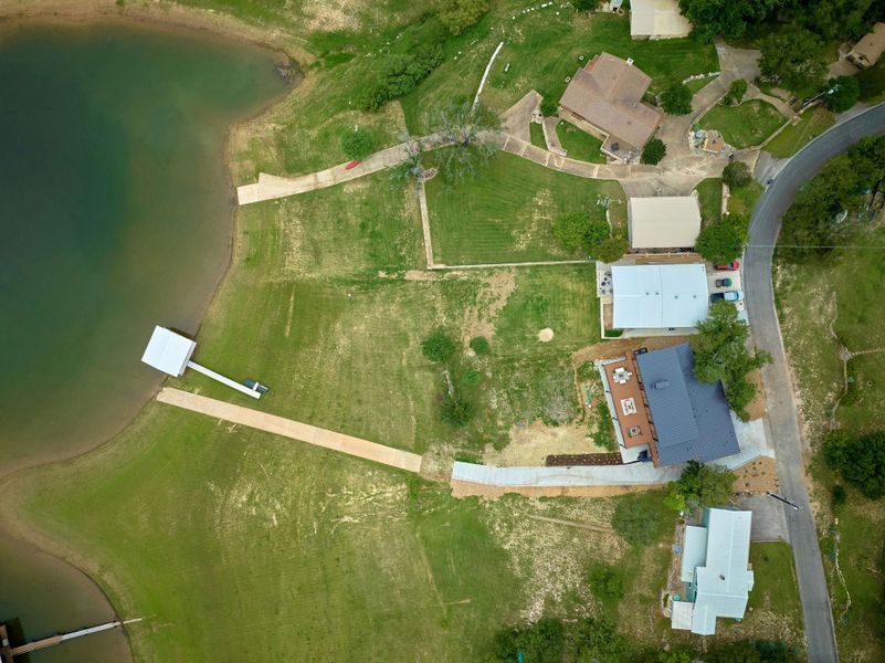 Waterfront property featuring a private boat dock with covered slip, extensive green lawn, and direct lake access