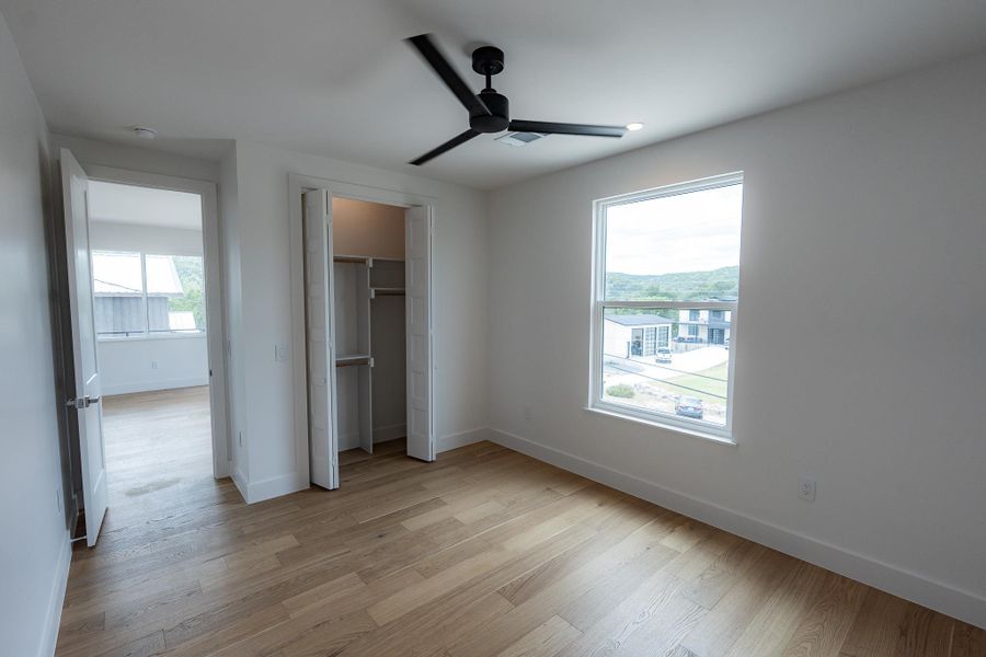 Apartment Primary Bedroom. Hardwood floors and a ceiling fan create a serene and practical bedroom space. Apartment Primary Bedroom. Hardwood floors and a ceiling fan create a serene and practical bedroom space.