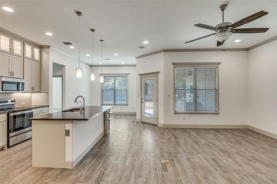 Kitchen with stainless steel appliances, decorative light fixtures, tasteful backsplash, a center island with sink, and crown molding Kitchen with stainless steel appliances, decorative light fixtures, tasteful backsplash, a center island with sink, and crown molding