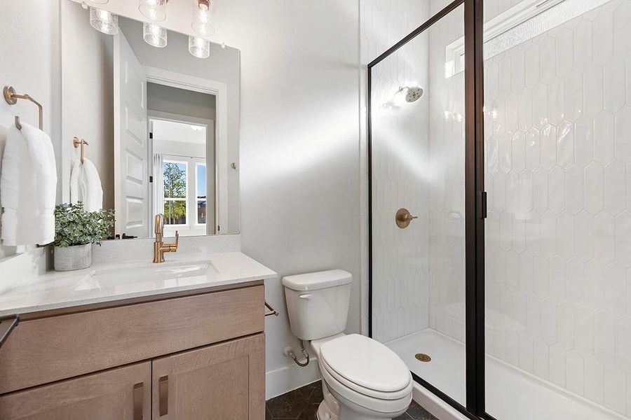 Crisp white tiled walls complement the contemporary vanity and glass-enclosed walk-in shower.