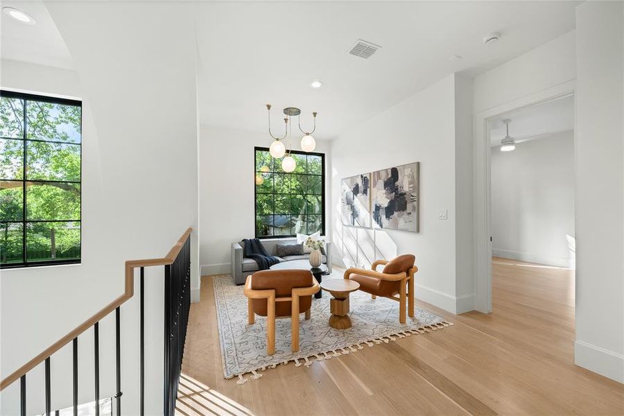 Bright upper-level landing featuring light wood-finish flooring and a contemporary chandelier