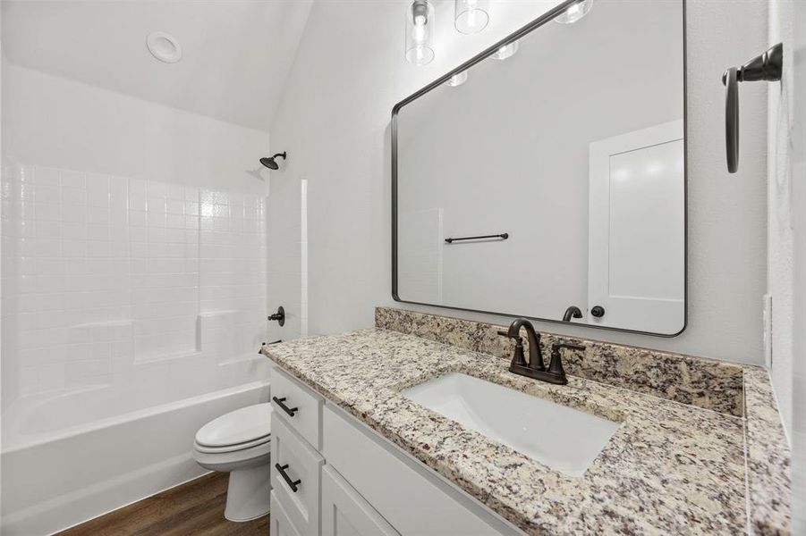 Full bath with  shower combination, vanity, vaulted ceiling, and dark wood finished floors