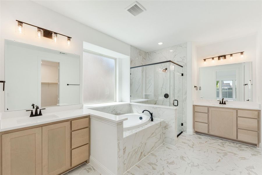 Master bathroom with dual vanities, soaking tub, glass shower, and marble tile throughout Master bathroom with dual vanities, soaking tub, glass shower, and marble tile throughout