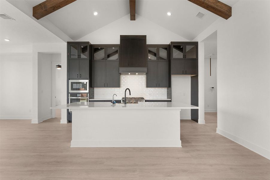 Kitchen with a kitchen island with sink, recessed lighting, light wood-type flooring, stainless steel appliances, and glass insert cabinets