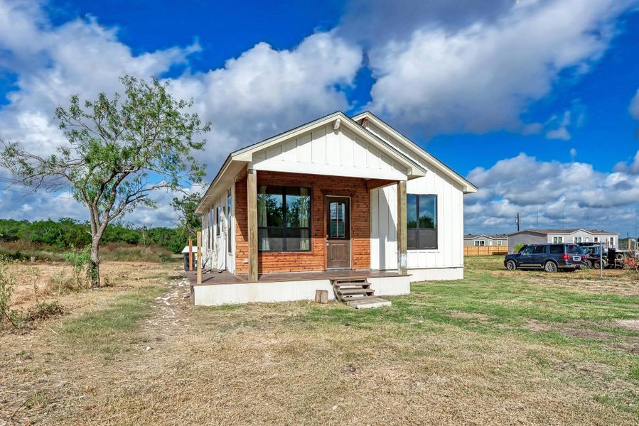 Board and batten siding meets warm wood accents on this inviting covered front porch entry.