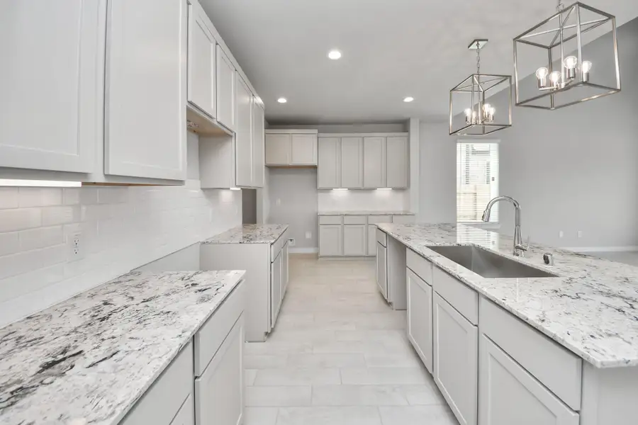 The kitchen is a culinary haven, featuring granite countertops, a tile backsplash, stainless steel appliances, 42” upper cabinets, and undercabinet lighting. Sample photo of completed home with similar floor plan. Actual colors and selections may vary.