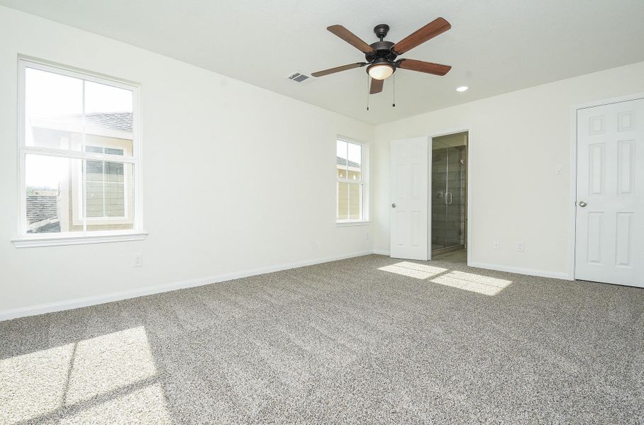 This is a bright, spacious room with neutral walls and carpet flooring, featuring a ceiling fan with lighting, and a window providing natural light. The room has two doors, one likely a closet, and the other leading to an adjacent space. This is a bright, spacious room with neutral walls and carpet flooring, featuring a ceiling fan with lighting, and a window providing natural light. The room has two doors, one likely a closet, and the other leading to an adjacent space.