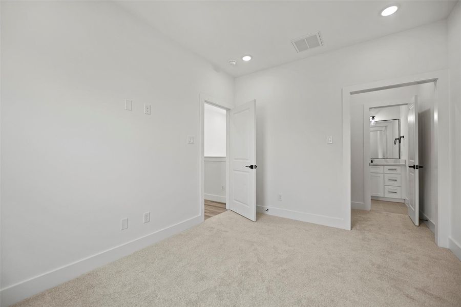 This secondary bedroom features recessed lighting, and a full bathroom with a vanity.