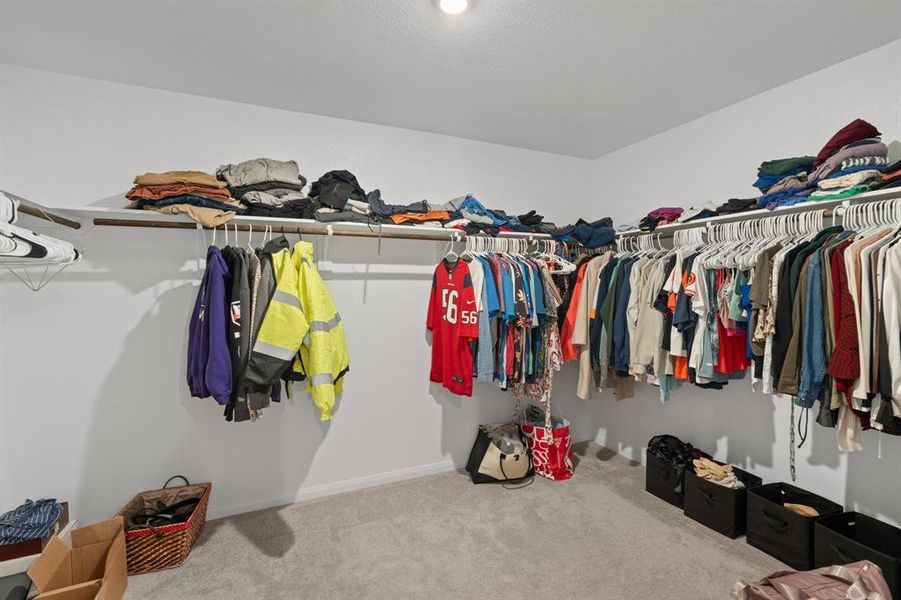 A Look into the Primary Spacious Walk-in Closet showcasing an abundance of hanging storage and shelf space.